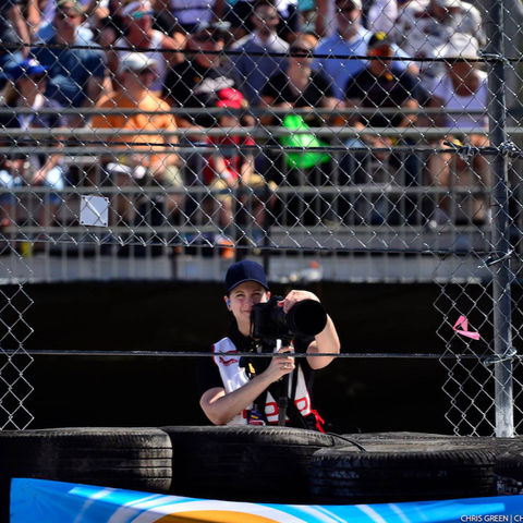 Female shooting photos at car race.