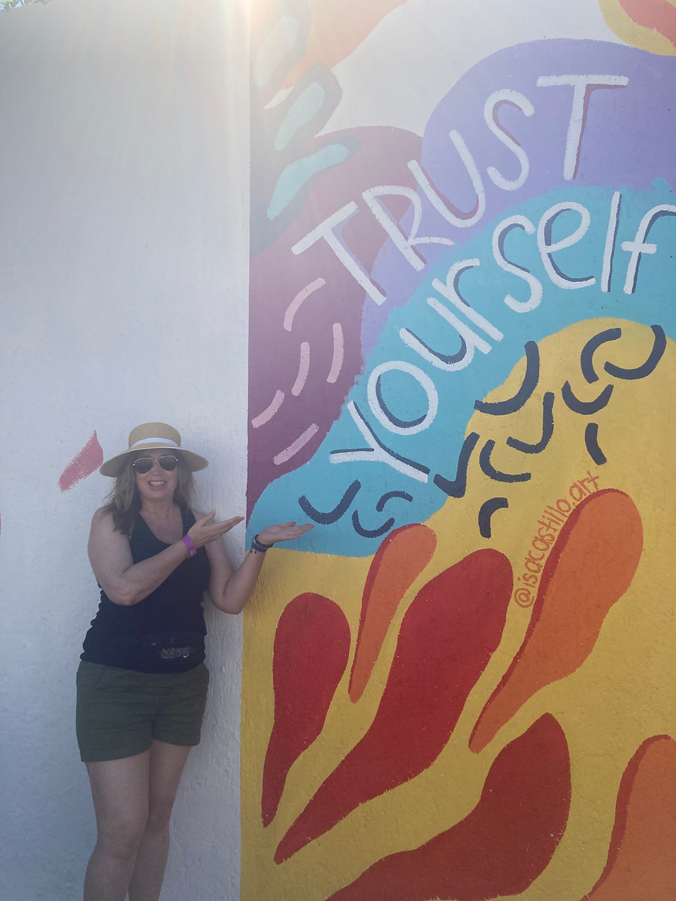 Tracy Rice standing by mural saying trust yourself  