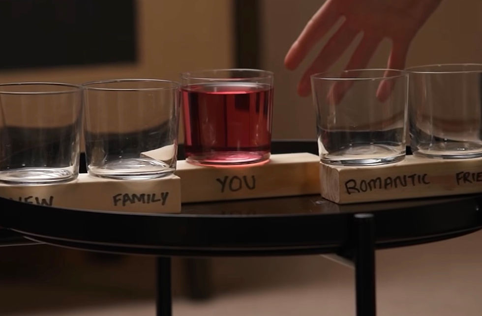 3 empty glasses and 1 glass with squash in. Hand reaching towards full glass.