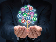 Hands in a suit cradle a digital tree of colorful social icons on a dark background, symbolizing connections and growth.