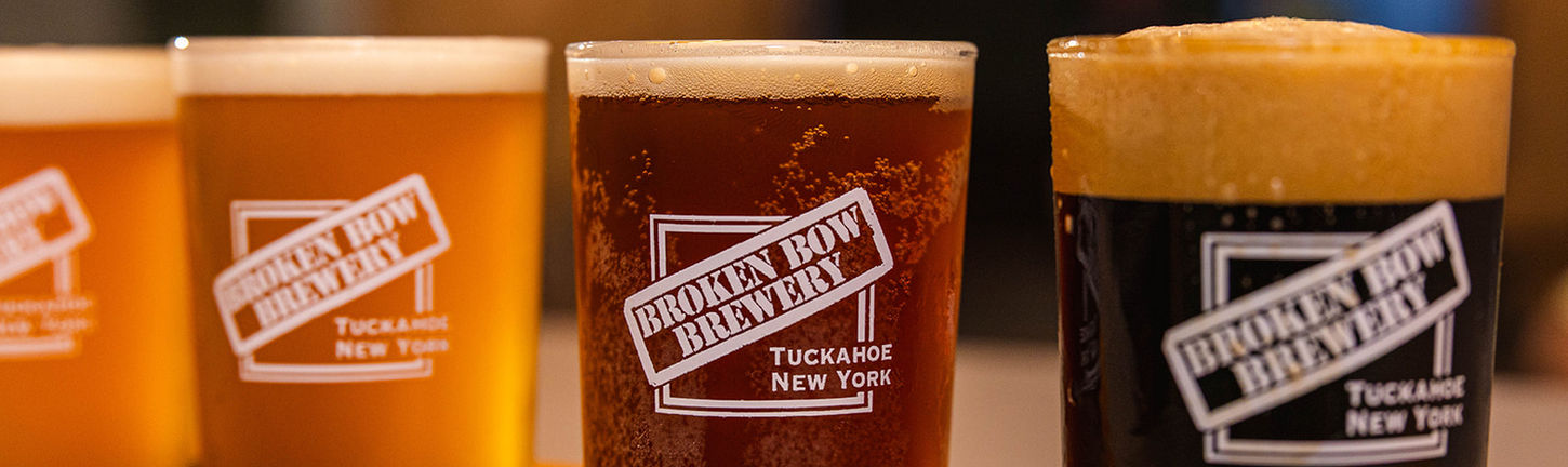 Four craft beers served in branded tasting glasses at Broken Bow Brewery, including a golden lager, amber ale, and dark stout.