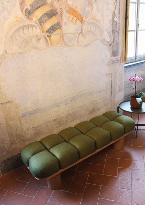 segmented bench with wood base, minimalist upholstered bench, essentials fabric designer seating, chestnut wood bench with cushions, rhythmic modern bench design, MM Italian furniture, entryway bench with organic shape, boutique lobby sculptural seating, centipede-inspired bench design, curved cushion wood bench