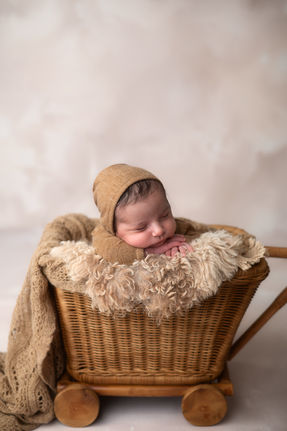 Neugeborenes Baby schlummert friedlich in einem Vintage-Korb mit Decke und Hut.