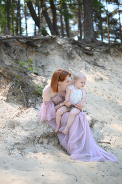 Mutter und Kind sitzen zusammen an einem Strand. FAMILIEN FOTOSHOOTING mit Sandhintergrund.