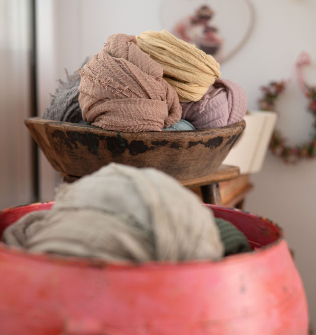 Holzschale mit verschiedenfarbigen Tüchern, Hintergrund mit Dekoration und Details.