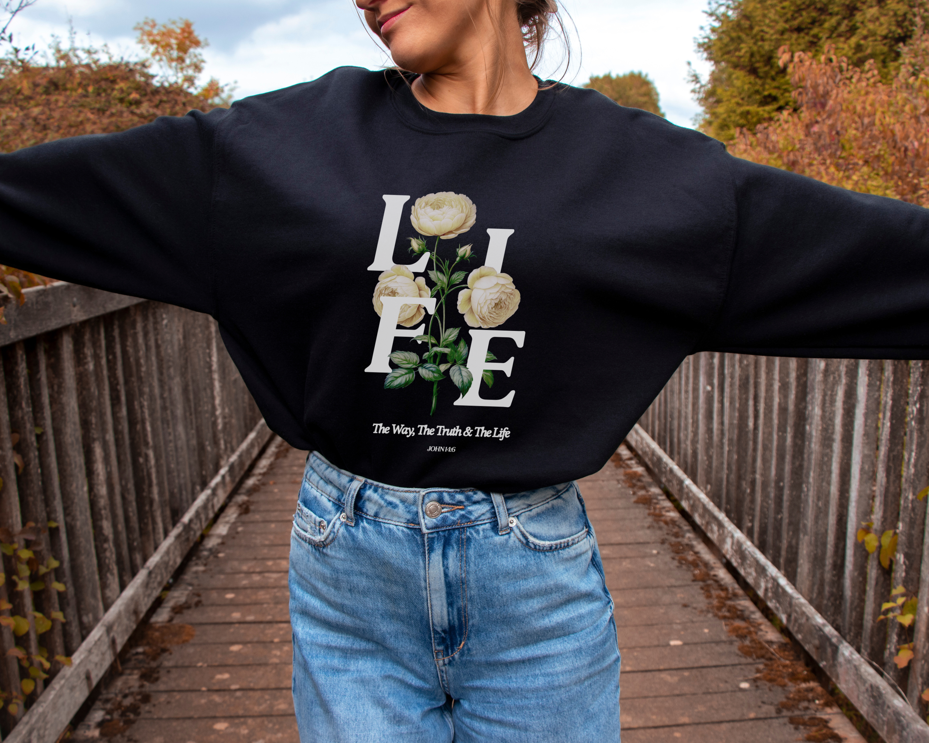 Black unisex Christian sweatshirt with floral and faith based graphic that says LIFE and has the bible verse John 4:16 that r