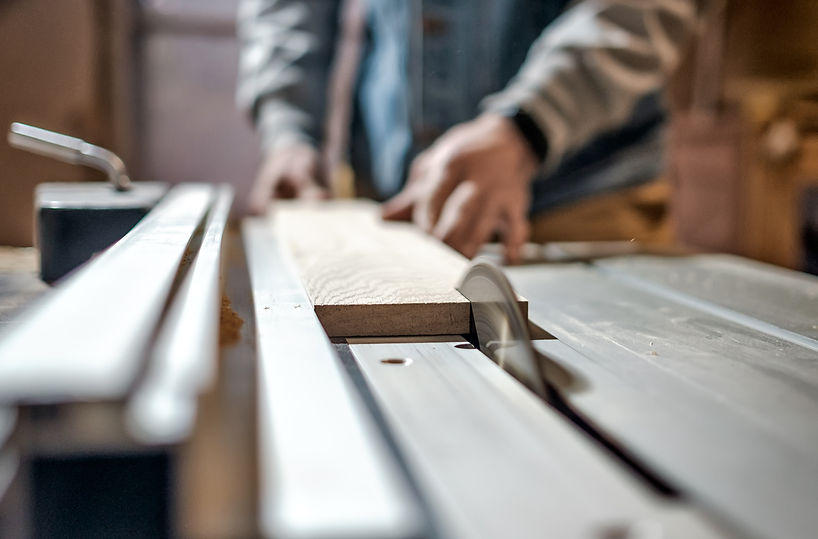 Caucasian man making wooden parts for custom furniture on machine tool called thickness pl