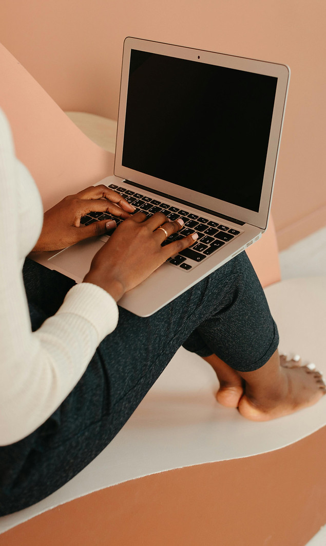 Young woman sitting on the floor working on a laptop, symbolizing the pressure to overachieve and always stay busy