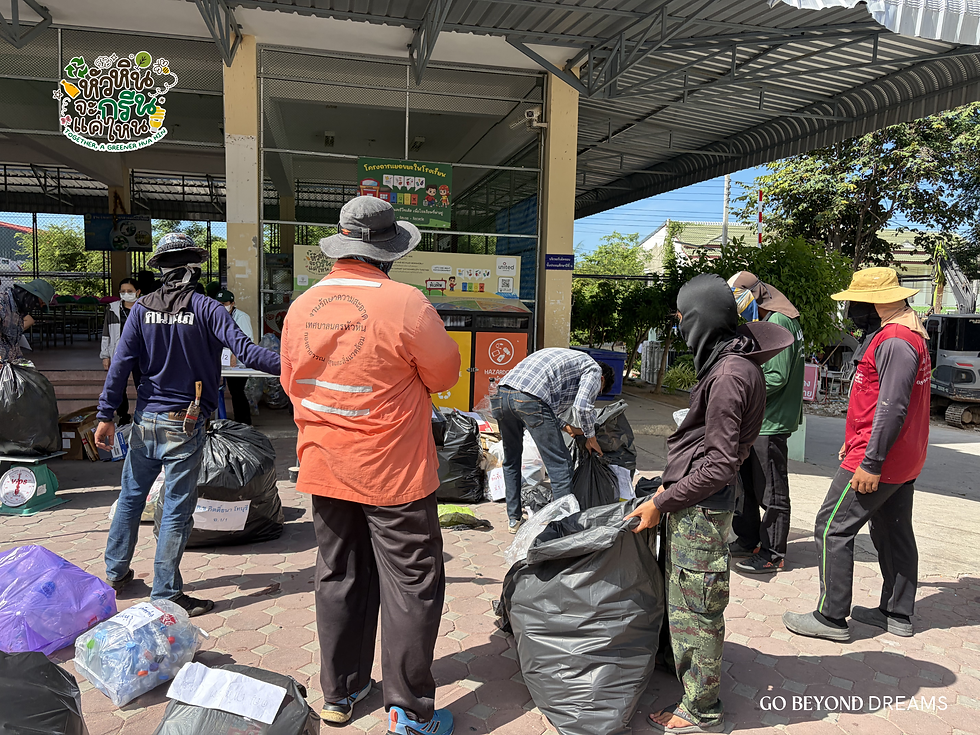 Workers in hats sort trash bags under a metal-roofed pavilion.