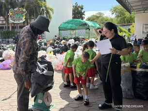 Adults and children sort plastic waste outdoors beside a scale.