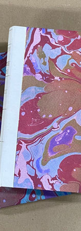 Two hardcover handbound books covered in bold marbled paper