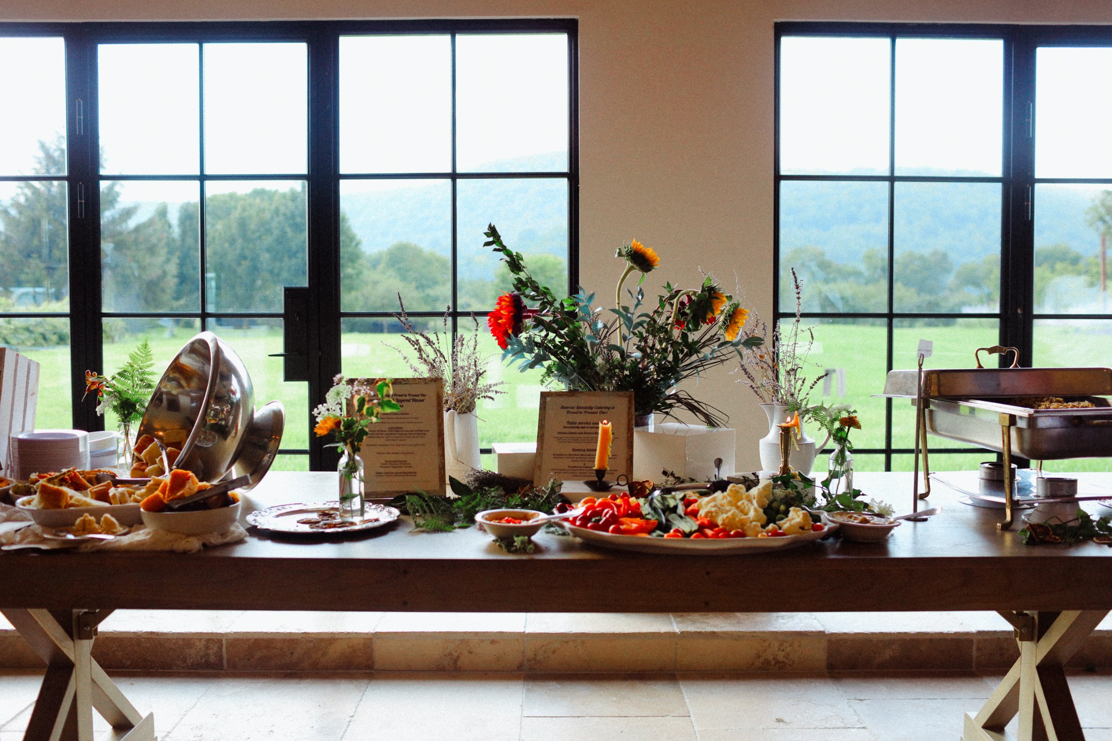 Chafers, platters, menu cards, and sunflowers against the Barn windows