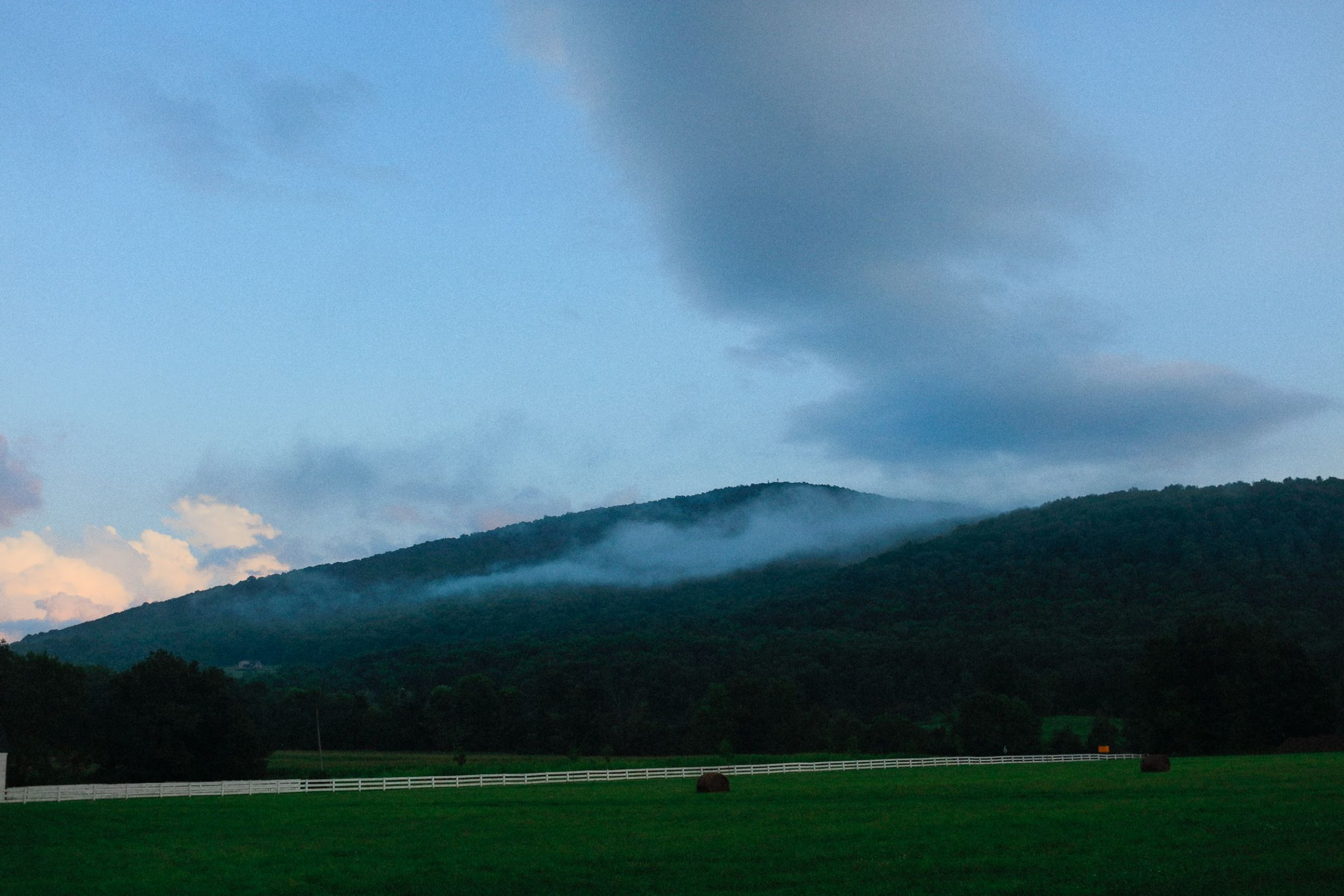 Cloud coming down over the mountain above the hayfield
