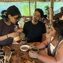 Teacher and students working at a table in a pottery class