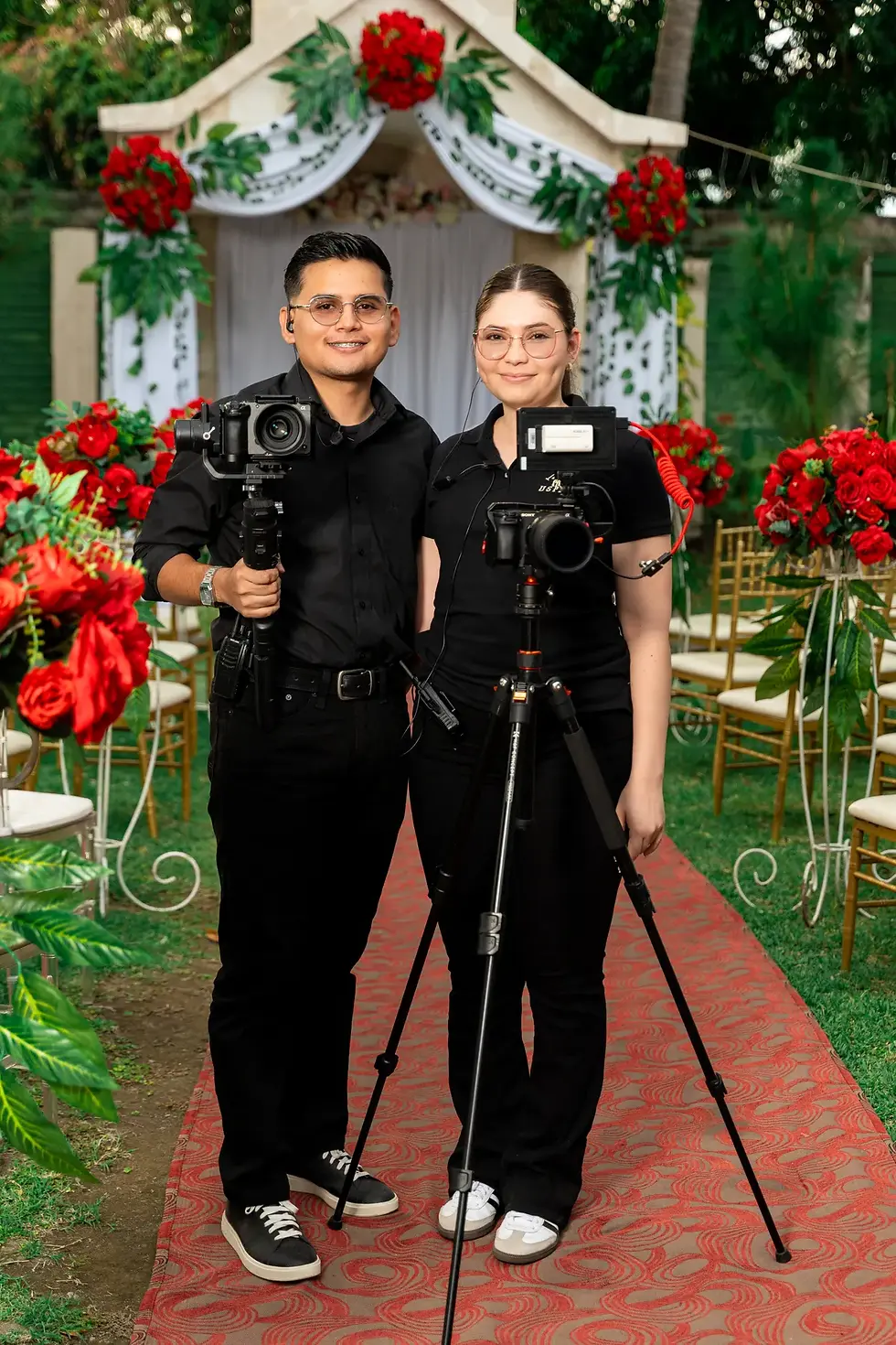 Two wedding photographers with cameras working an outdoor wedding setup