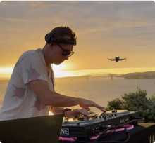 Founder Paul Marr DJing at sunset, with his FPV drone in the air behind him