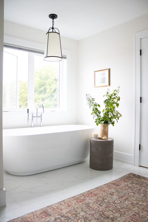 A large modern bathtub sitting next to a bright window in a new home
