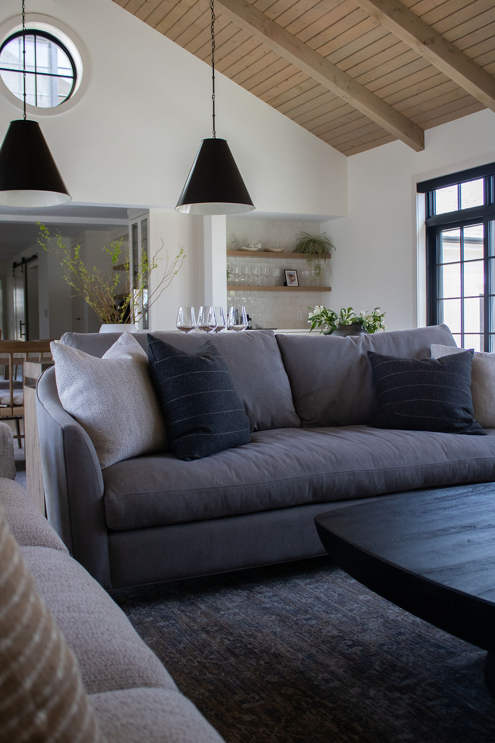 A modern living space with high ceilings and two couches surrounding a black coffee table as an example of a low VOC designed home