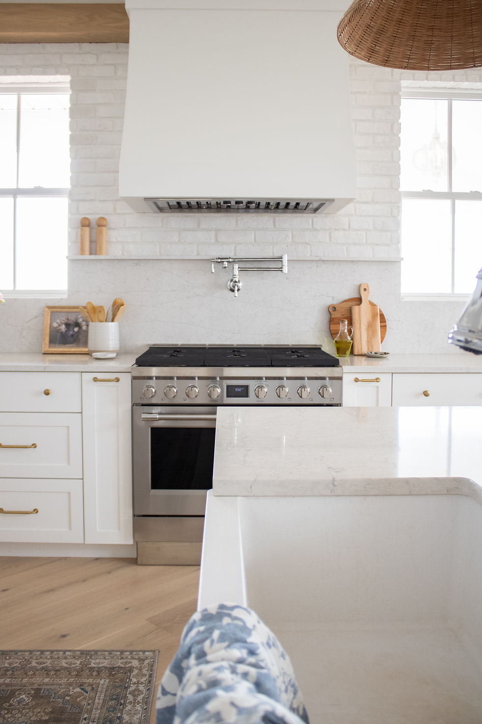 A new stove stands in a white kitchen renovation with a pot filler conveniently added as part of the renovation overtop of the stove