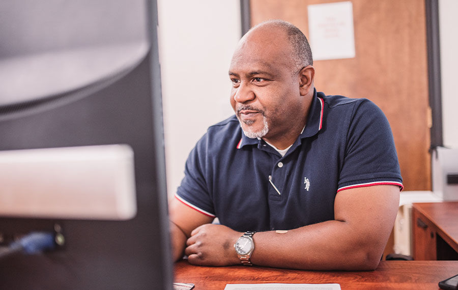 Man smiling and using desktop for fleet management software in office