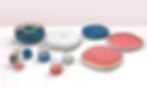 Cast jewelry in colorful cases labeled on a marble surface. contains rings, a bracelet, and decorative domes.