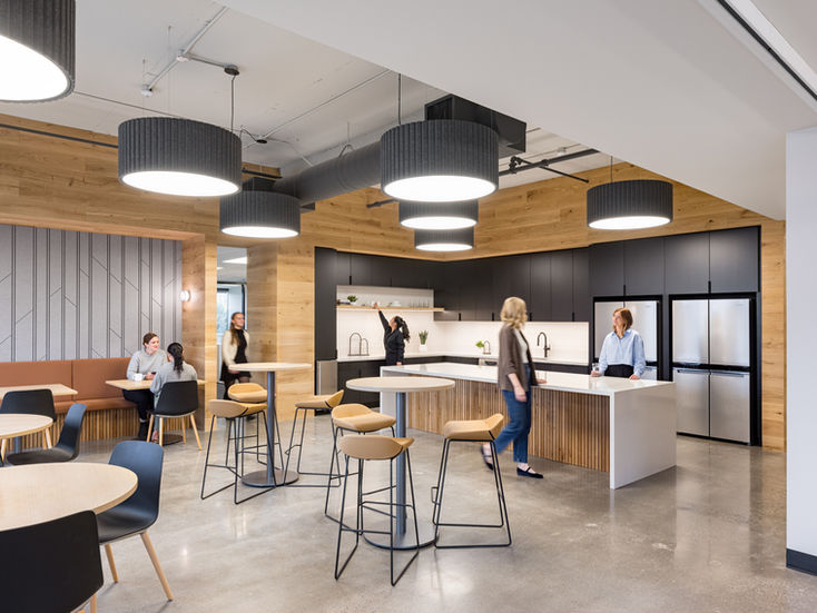 Modern office kitchen with people and bar stools.
