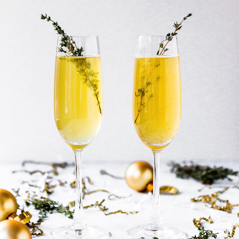 2 beverages in a champagne flute with rosemary