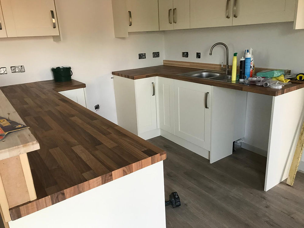 Newly fitted kitchen with white cabinets and wood counters