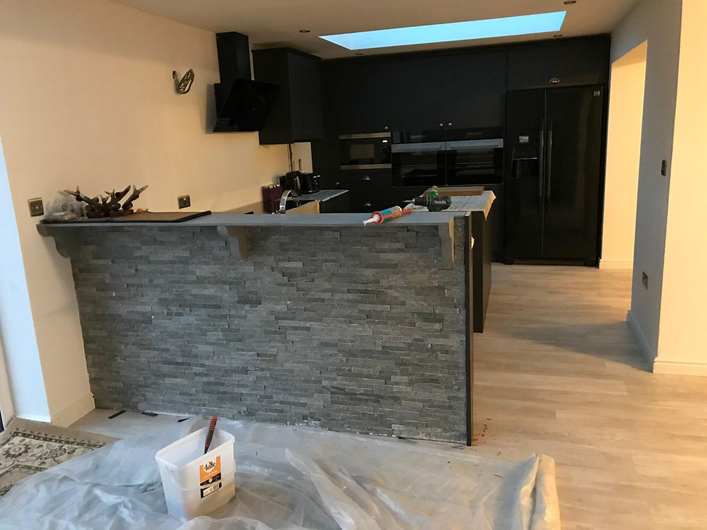 Modern kitchen installation with dark cabinets and stone island.