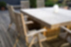 Solid acacia wood square outdoor dining table with matching slatted armchairs on a backyard deck