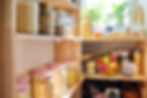 Organized pantry shelves with glass jars and BPA-free containers storing dry goods, grains, and pasta under natural light