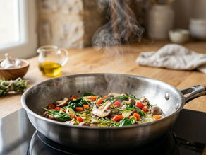 Mixed vegetables sautéing in a stainless steel skillet with olive oil and herbs.