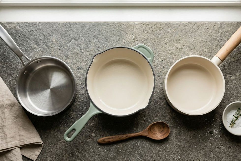 Flat lay of stainless steel, enameled cast iron, and ceramic-coated saucepans on a stone countertop.