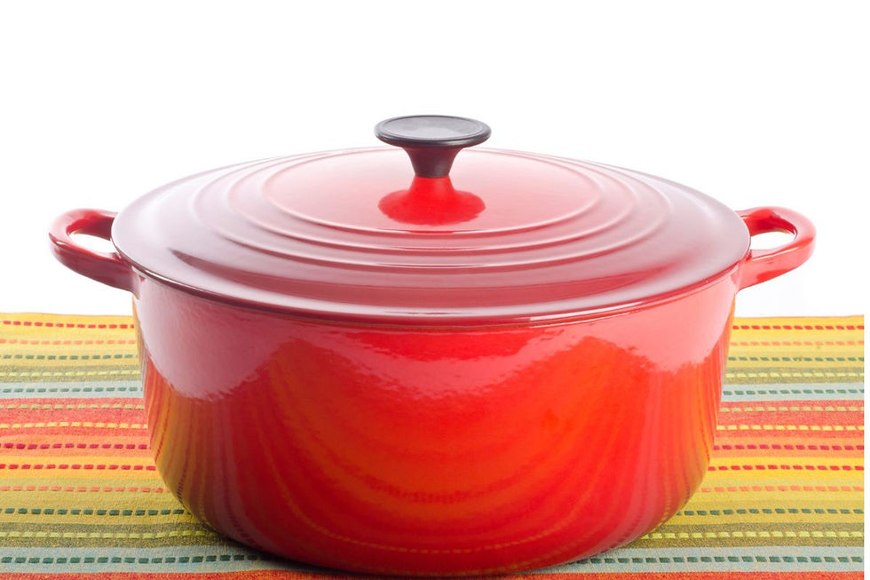 Classic red Le Creuset Dutch oven with lid closed, displayed on a colorful striped mat—symbol of premium non-toxic cookware.