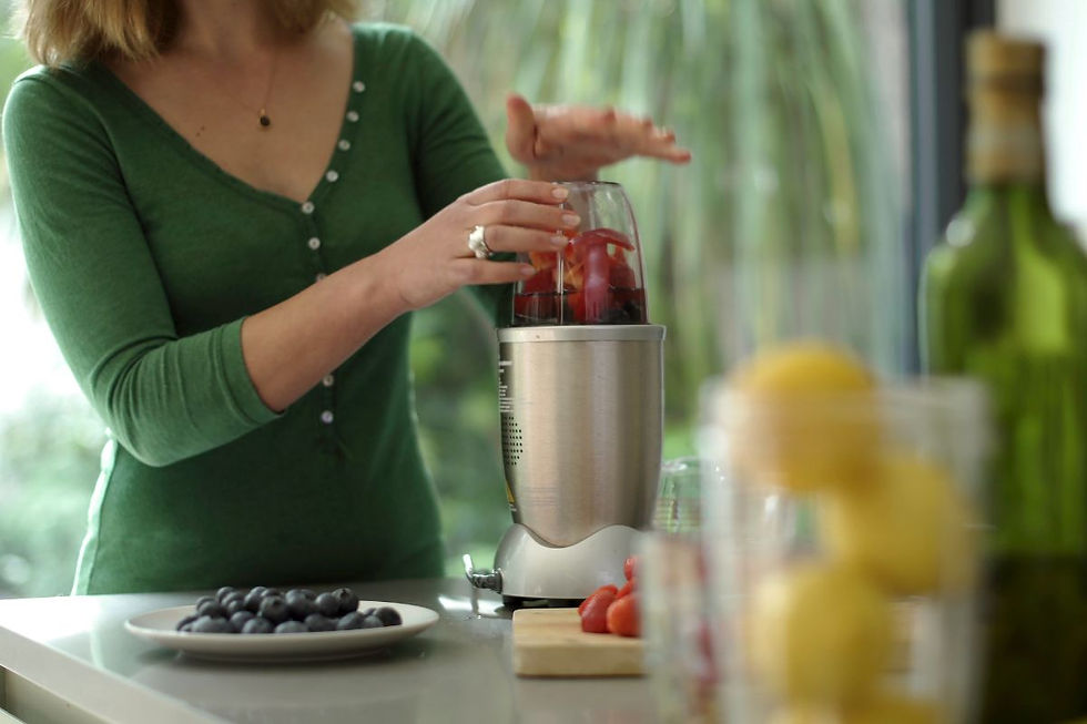 Woman in green shirt using a compact NutriBullet-style blender with berries — ideal for smoothie prep in small kitchens or on-the-go lifestyles.