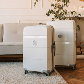 hite durable hardshell luggage set in a modern living room with sofa and plants.