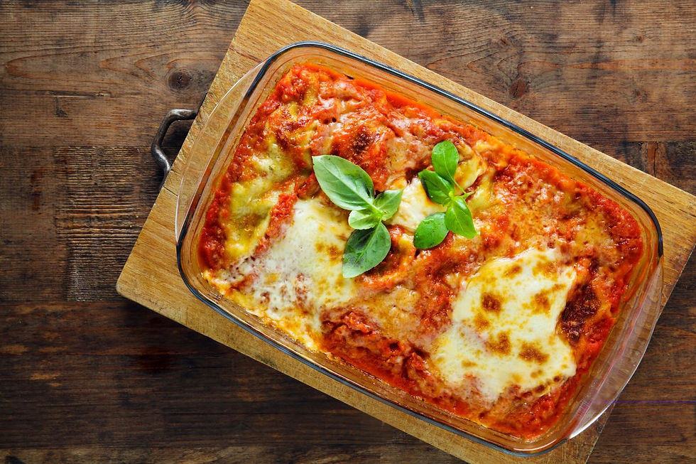 Homemade plant-based lasagna in a glass Pyrex-style baking dish on a wooden board