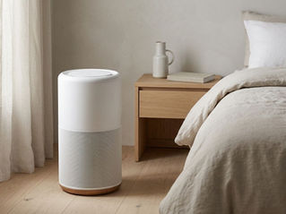 Modern air purifier beside a bed in a softly lit minimalist bedroom.