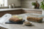Clear glass food storage containers with lids on a kitchen counter with grains and seeds nearby