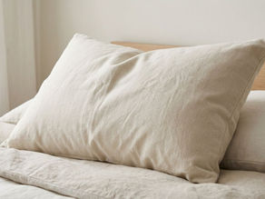 Close-up of a natural-looking pillow with textured organic-style fabric on soft neutral bedding