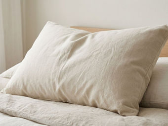 Close-up of a natural-looking pillow with textured organic-style fabric on soft neutral bedding