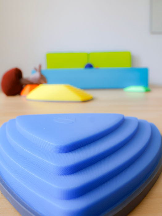 Zu sehen sind Balanciersteine und Gymnastikmatten. Auf einen Balancierstein scheint ein Schnecken-Sofftier zu kriechen.