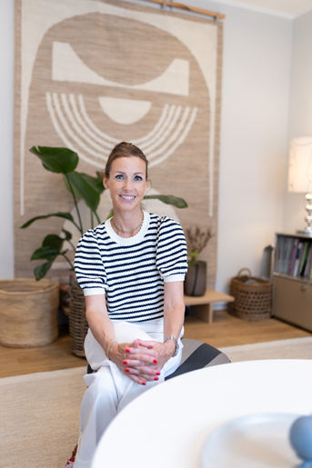 Petra Borgmann sitzt in ihren Räumlichkeiten in Münster entspannt mit überschlagenen Beinen und Blick in die Kamera bei einem Businessshooting.