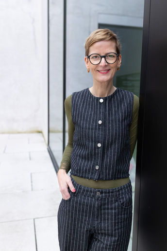 Ina Oakley lehnt allein im Innenhof vom LWL in Münster bei einem stilvollen Portraitshooting.
