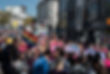 A photograph from Wind Street Swansea of the start of the Swansea Pride parade showing a large gathering of people with rainbow flags and a large trans flag