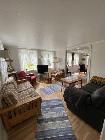 Das Wohnzimmer mit verschiedenen Sitzmöglichkeiten unter anderem mit zwei Sofas, Sesseln und einem Fernseher. 