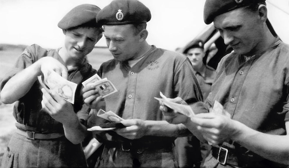 Abb. 13: britische Soldaten der 5. Fallschirmbrigade betrachten 100-Francs-Scheine und Invasionsgeld in den Händen, welches sie auf dem französischen Festland verwenden werden (fotografiert am 3. Juni 1944 auf dem englischen Flughafen Faiford bei Swindon in Gloucestershire).