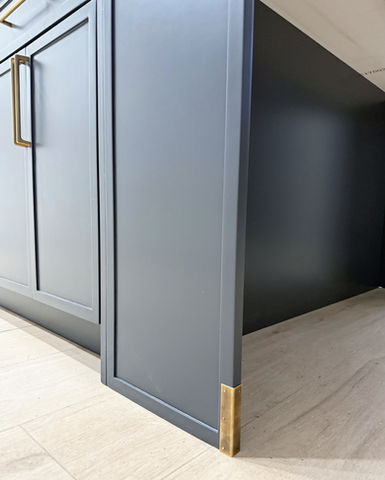 Custom charcoal grey cabinet leg with decorative brass corner bracket detail, part of a kitchen remodel by Moll & Co. | Vista in Tampa, FL