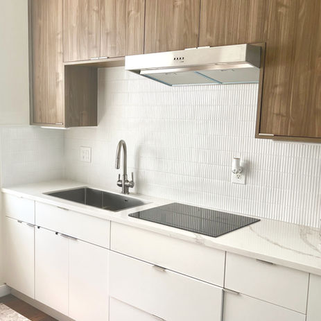 Modern European-style kitchen with flat-panel walnut uppers, white base cabinets, integrated cooktop, and vertical tile backsplash, designed by Moll & Co. | Vista in Tampa, FL