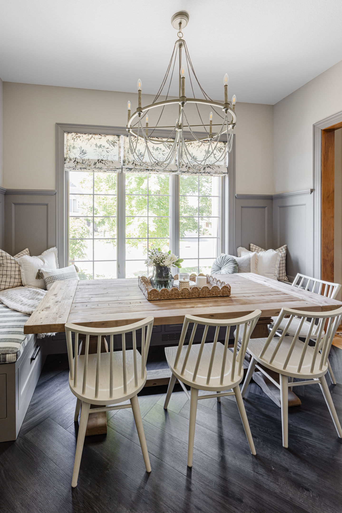 Custom dining room remodel featuring spray painted gray wainscoting, repainted black hutch, gray wood chandelier, and a white oak large dining table